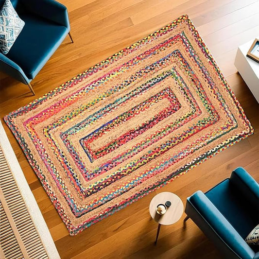 Colorful braided rug on a wooden floor with blue chairs and a small table.