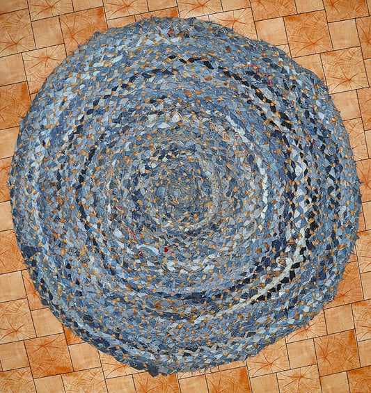 Round braided rug made from recycled denim on a wooden floor.