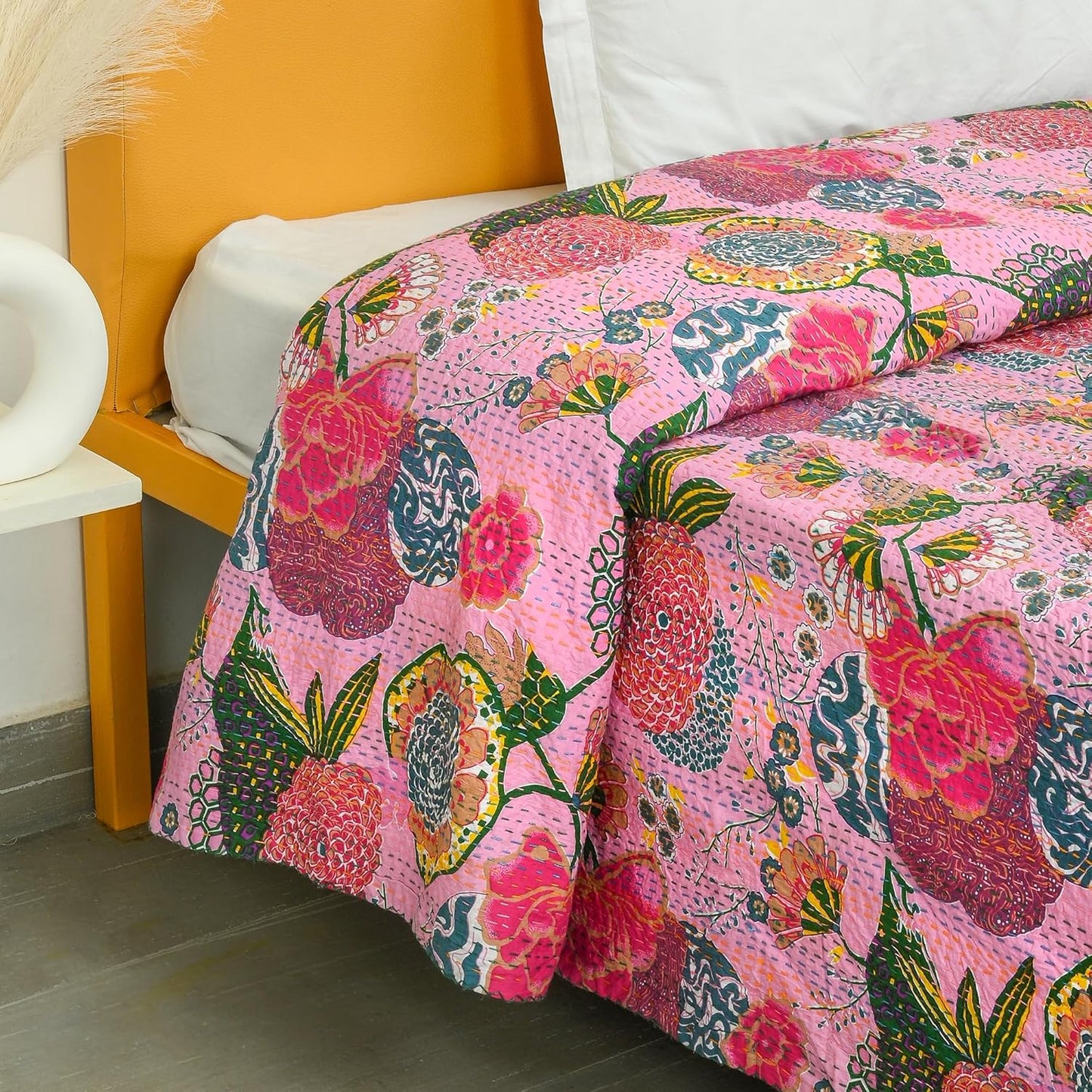 Colorful floral quilt on a bed with a yellow headboard.