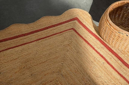 Textured beige rug with red stripes next to a woven basket on a dark surface