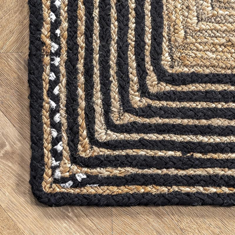 Close-up of a braided rug with black and beige stripes on a wooden floor.