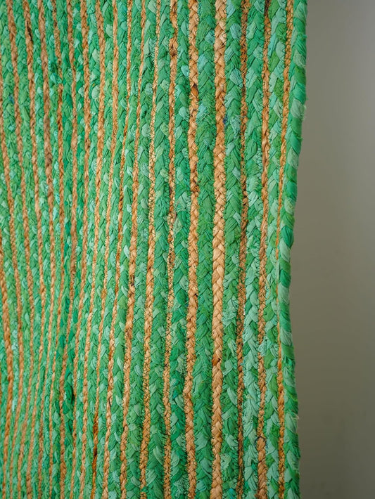 Handwoven green and tan braided rug, made from natural fibers, adding texture and color to any space.