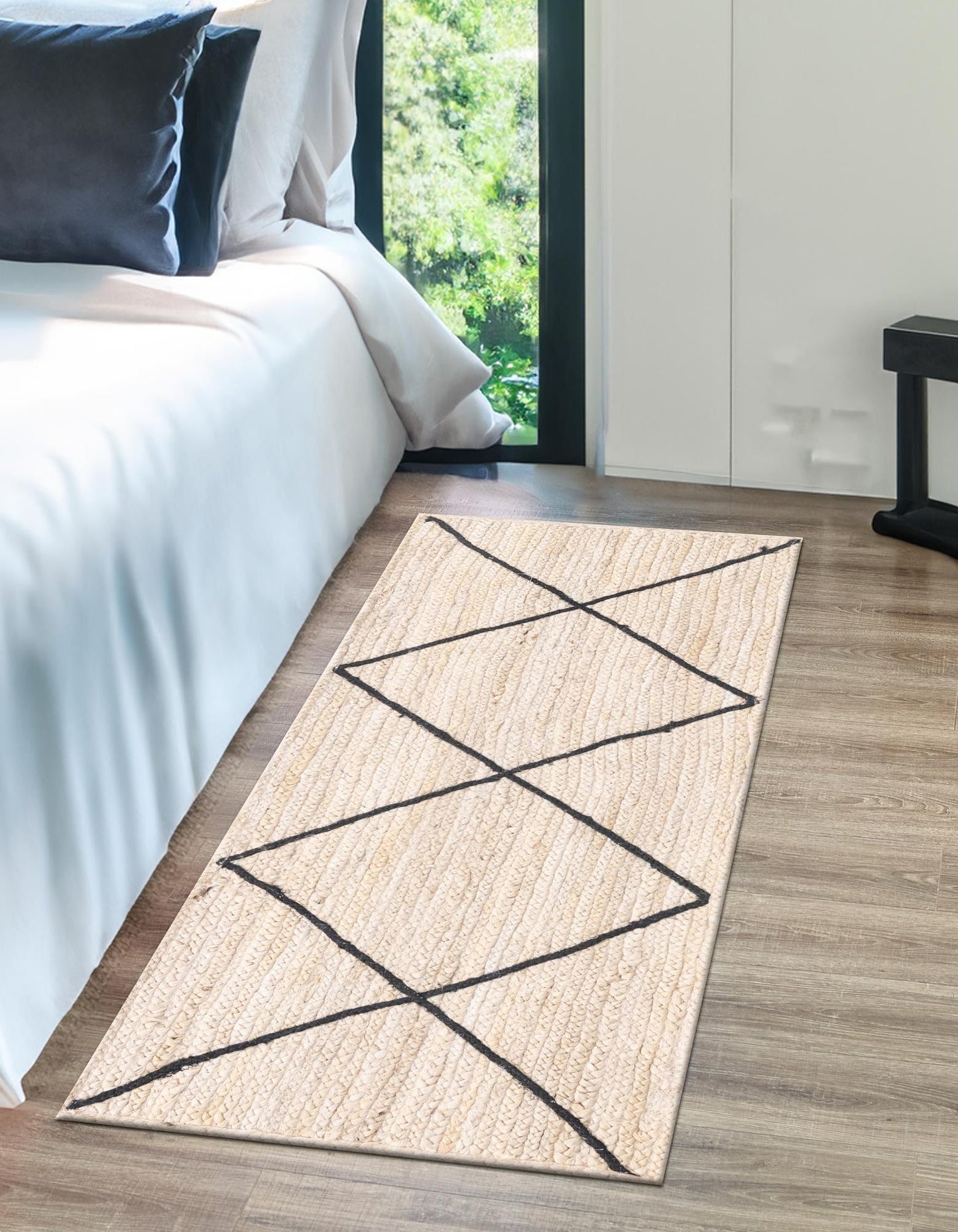 Beige woven rug with black lines on a wooden floor in a bedroom.