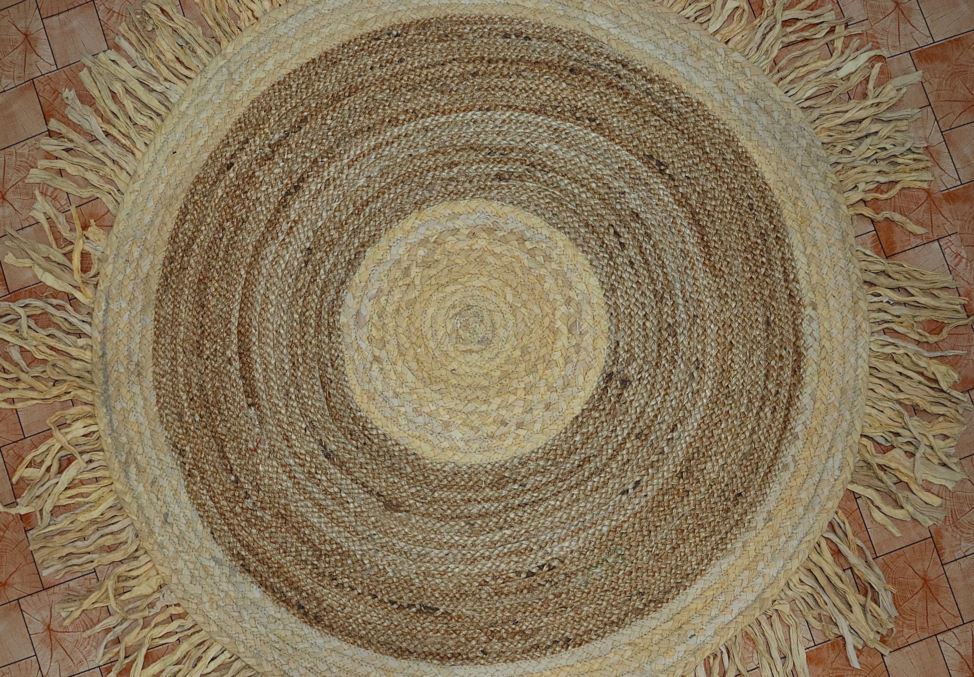 Round braided rug with fringes on a tiled floor