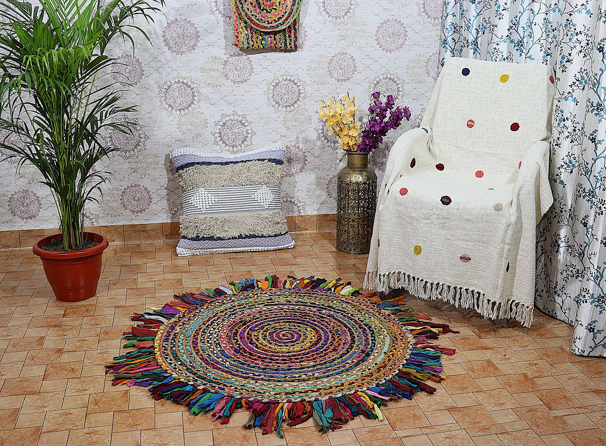 Colorful round rug with tassels in a room with a chair, plant, and wall decor.