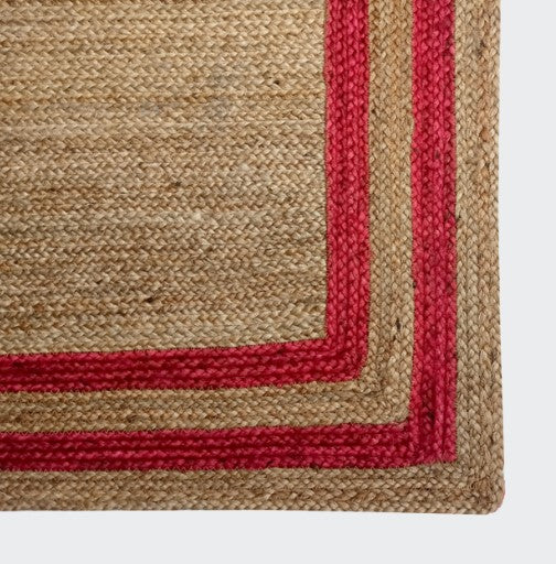 Natural jute rug with vibrant red border, soft texture, perfect for home decor.