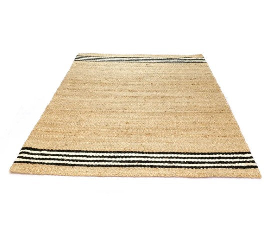 Natural jute rug with black and white striped border, eco-friendly, perfect for rustic decor.