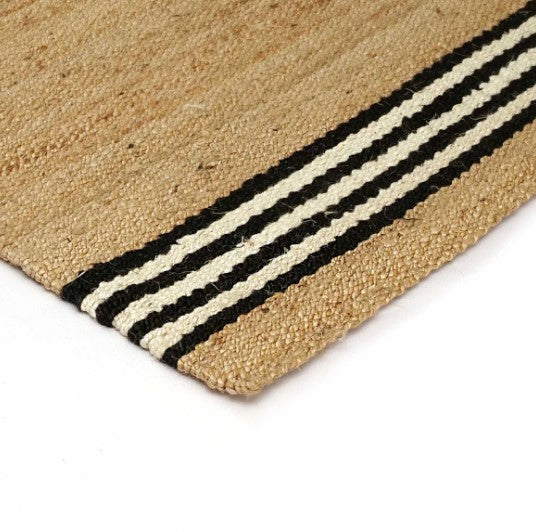 Natural jute rug with black and cream stripes, perfect for adding texture to home decor.