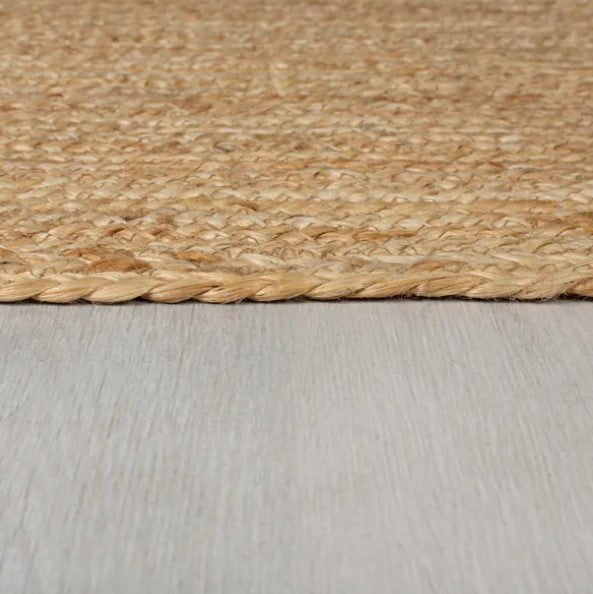 Natural jute area rug with braided edges, perfect for adding warmth to any space.