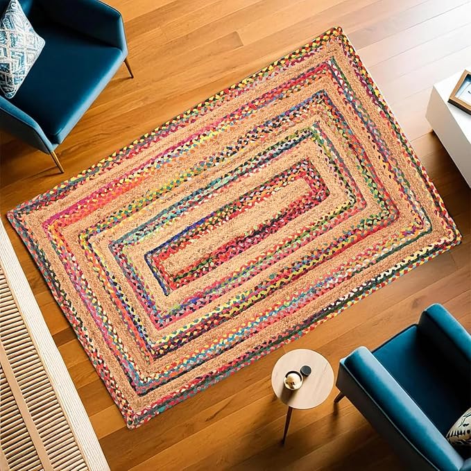 Colorful braided rug on a wooden floor with blue chairs and a small table.