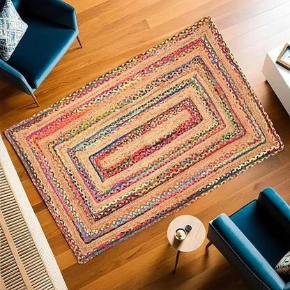 Colorful braided rug on a wooden floor with blue chairs and a small table.
