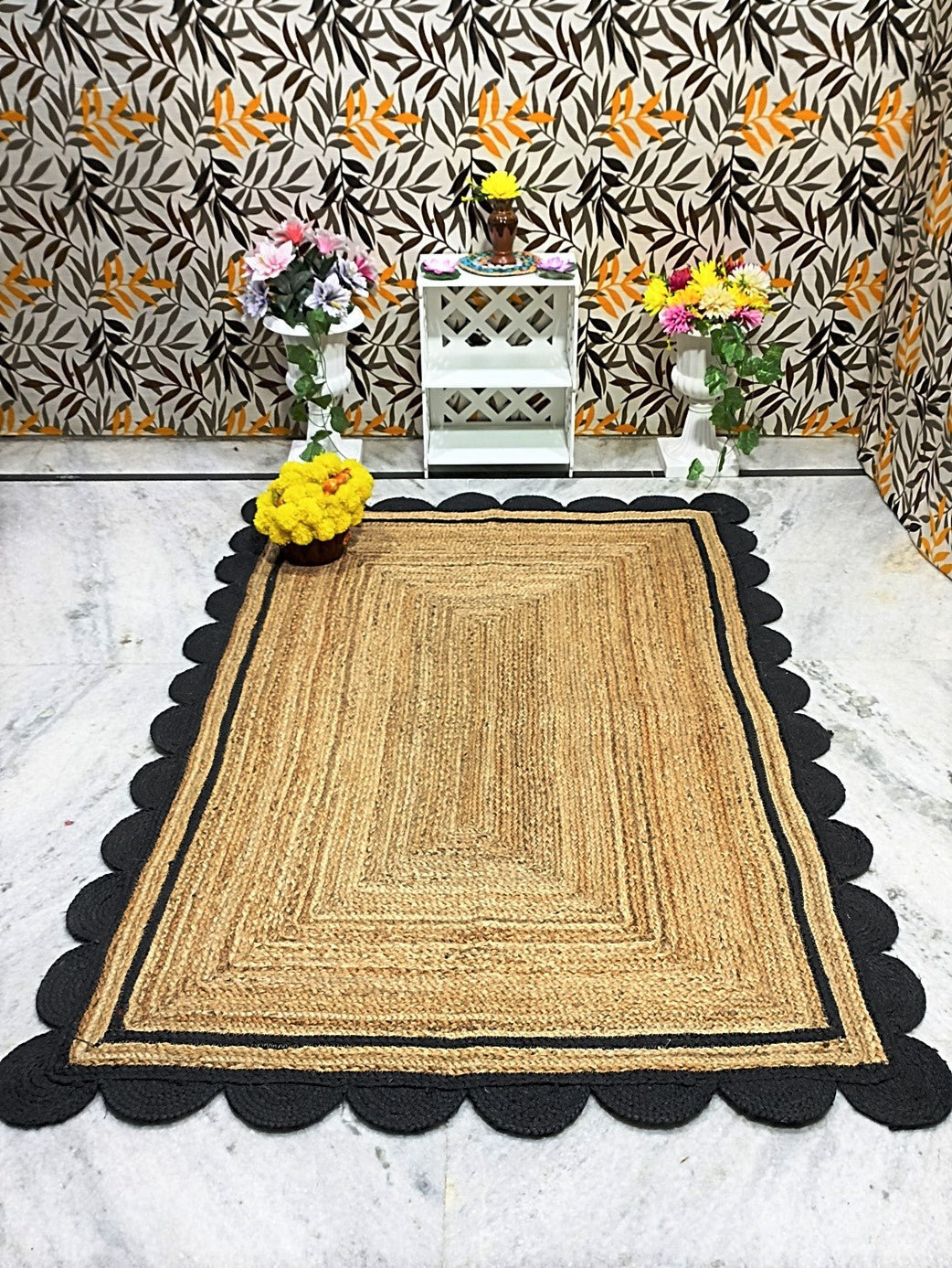 Woven rug with scalloped edge on a marble floor, with decorative elements and floral arrangements.