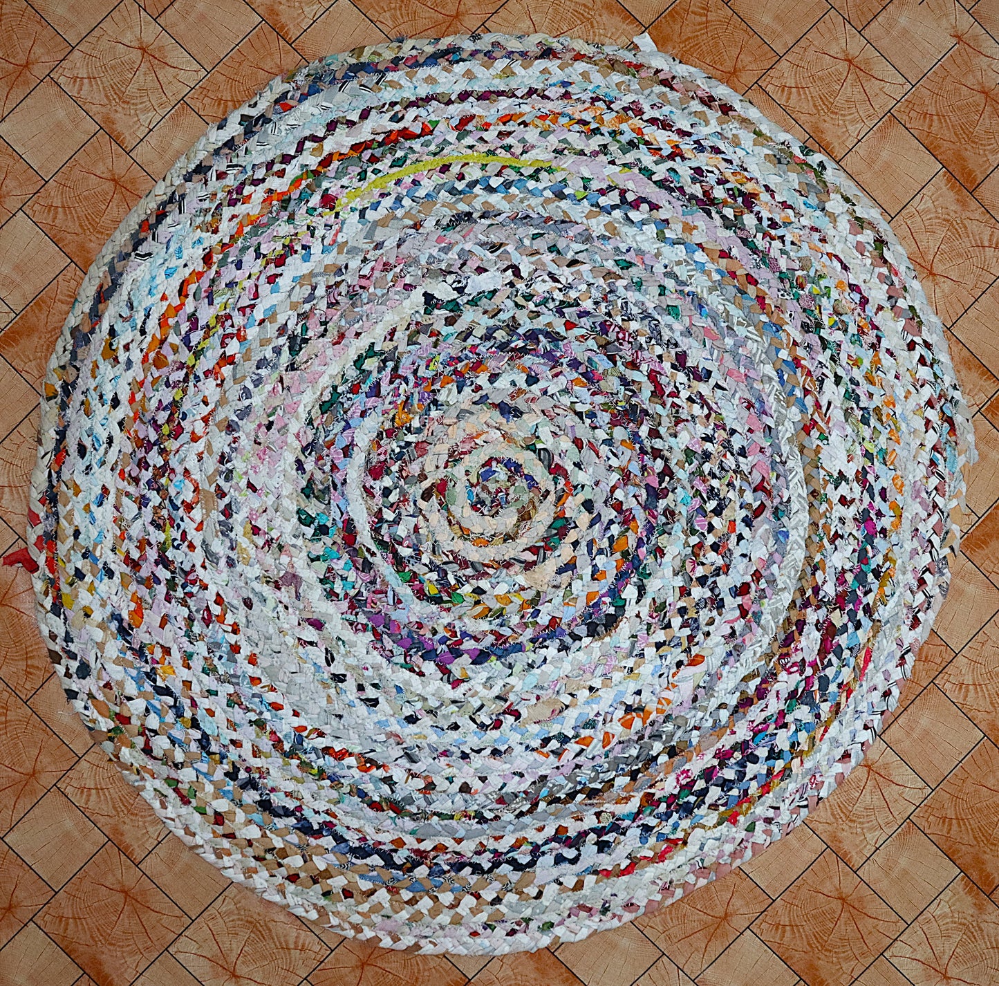 Round multicolored braided rug on a wooden floor