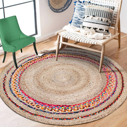 Round multicolored braided rug in a room with a green chair, wooden bench, and decorative pillows.