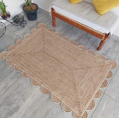 Beige braided rectangular rug with scalloped edges, perfect for home decor and style enhancement.