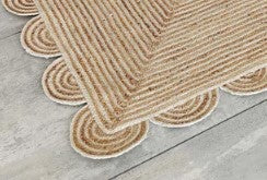 Beige woven jute rug with scalloped edges, ideal for adding texture to any room.
