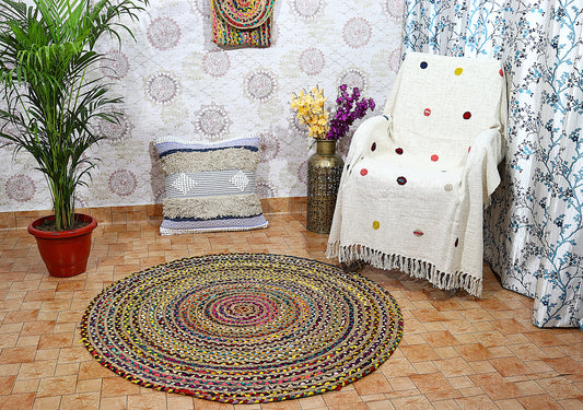 Round braided rug on a wooden floor with a patterned wall and decorative elements.