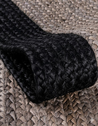 Close-up of a black woven rug on a textured surface