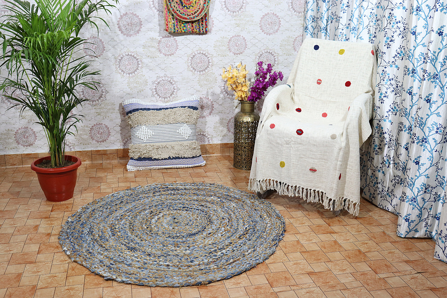 Round braided rug on a wooden floor with a chair, plant, and decorative items.