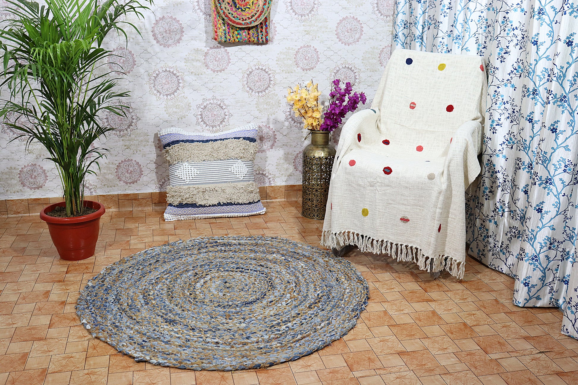 Round braided rug on a wooden floor with a chair, plant, and decorative items.