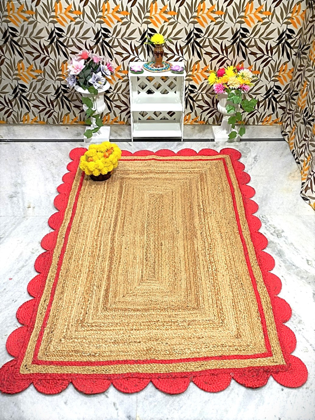 Woven mat with red border on a marble floor, against a patterned wall.