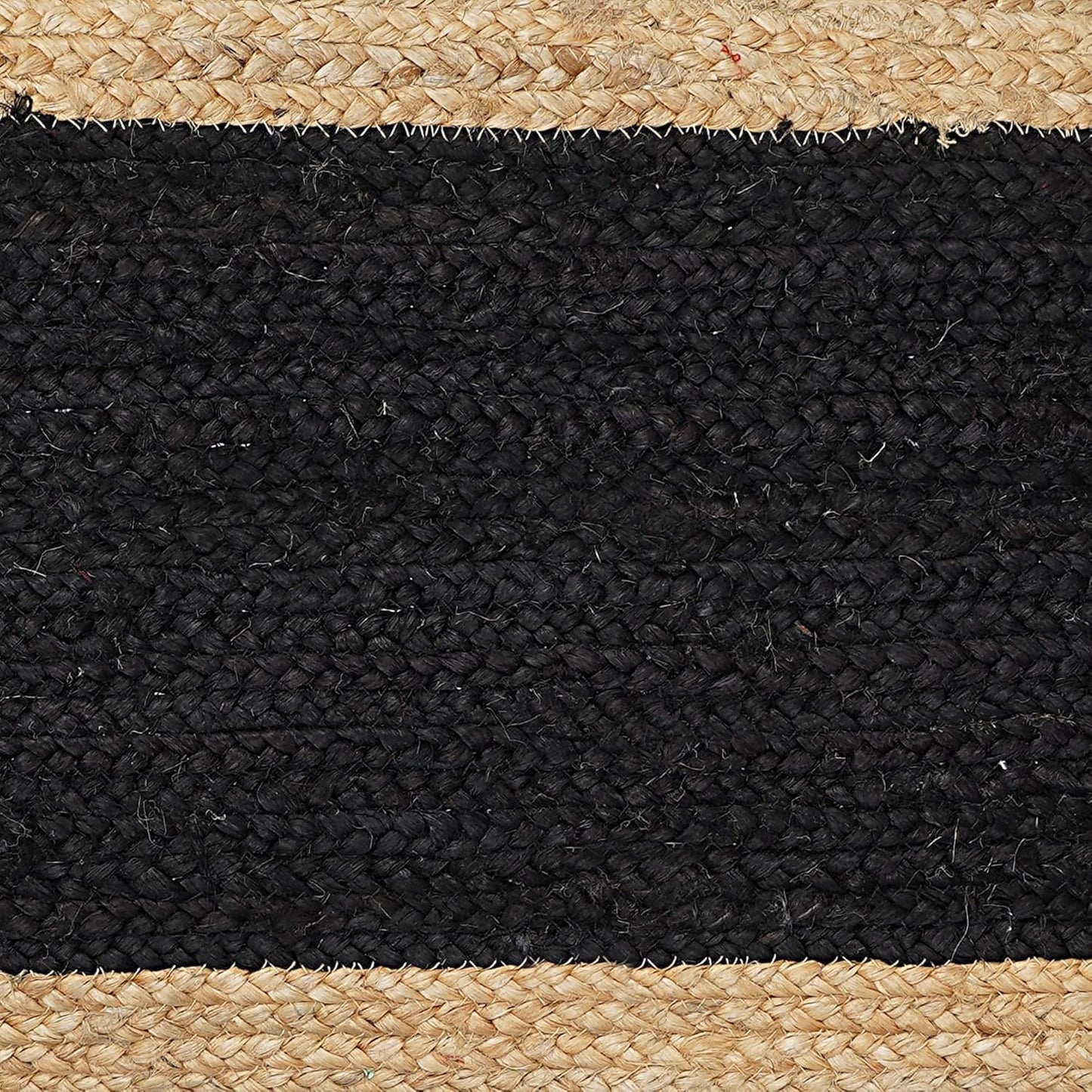 Close-up of a black and beige woven rug with natural fiber edges.