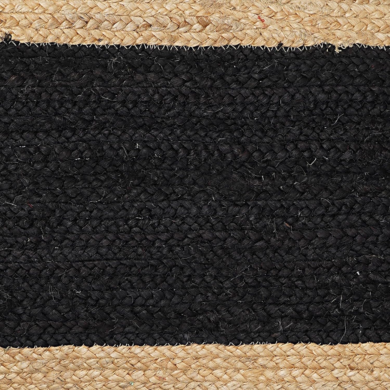 Close-up of a black and beige woven rug with natural fiber edges.