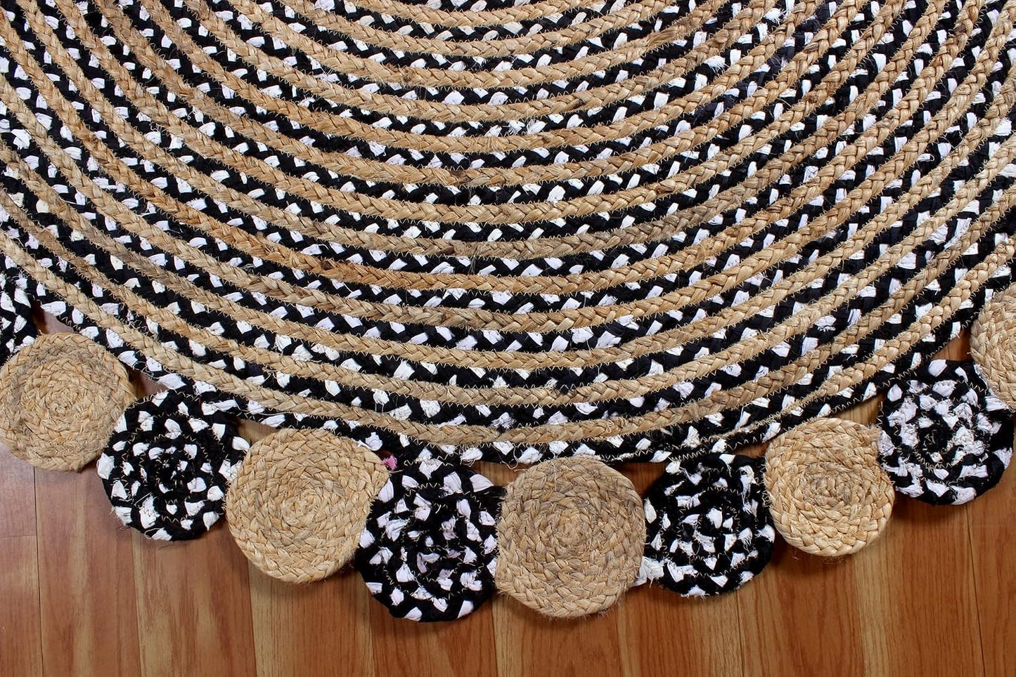 Black and white braided rug with natural jute border on a wooden floor