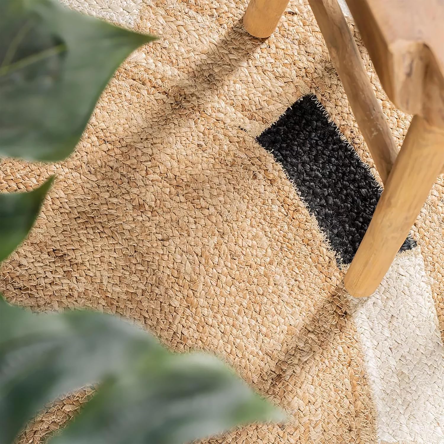 Handwoven jute area rug with black and white accents, perfect for a natural decor style.
