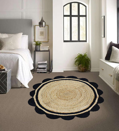 Round jute rug with black border on a gray carpet in a bedroom.