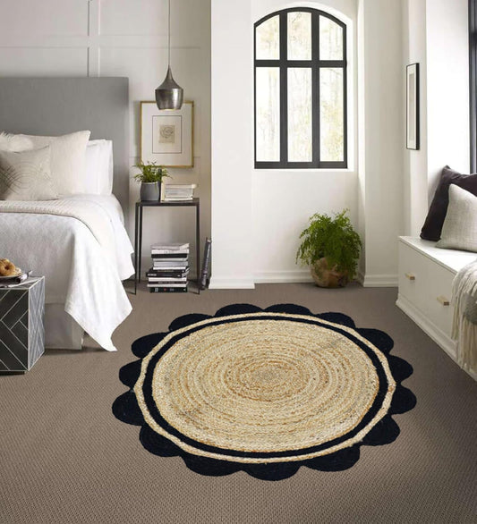 Round jute rug with black border on a gray carpet in a bedroom.