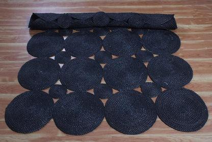 Black braided woven rug with circular patterns, perfect for contemporary home decor.