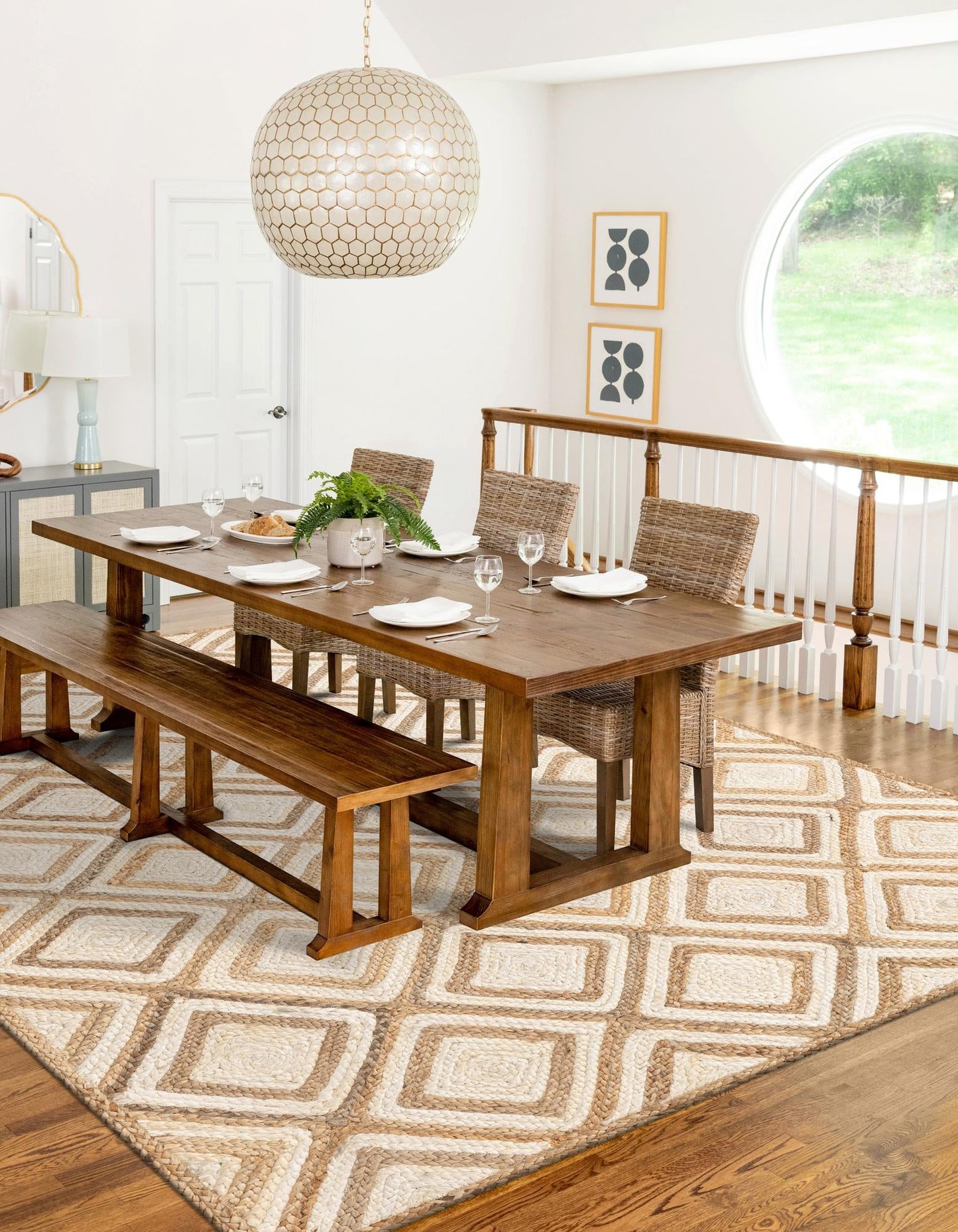 Dining room with wooden table, chairs, and bench on a patterned rug.