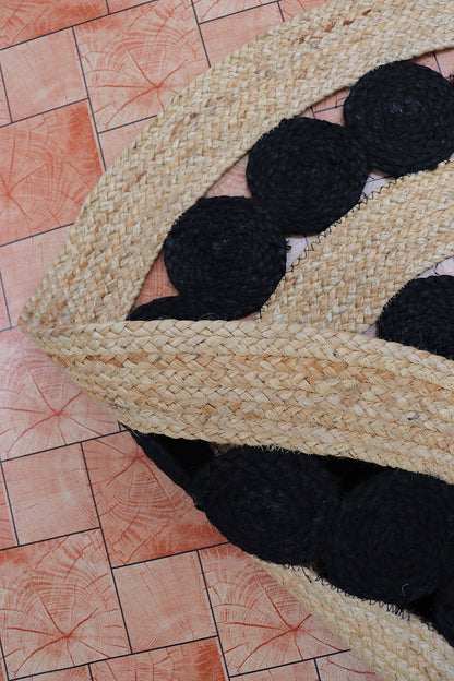 Close-up of a woven mat with black circular patterns on a tiled floor.
