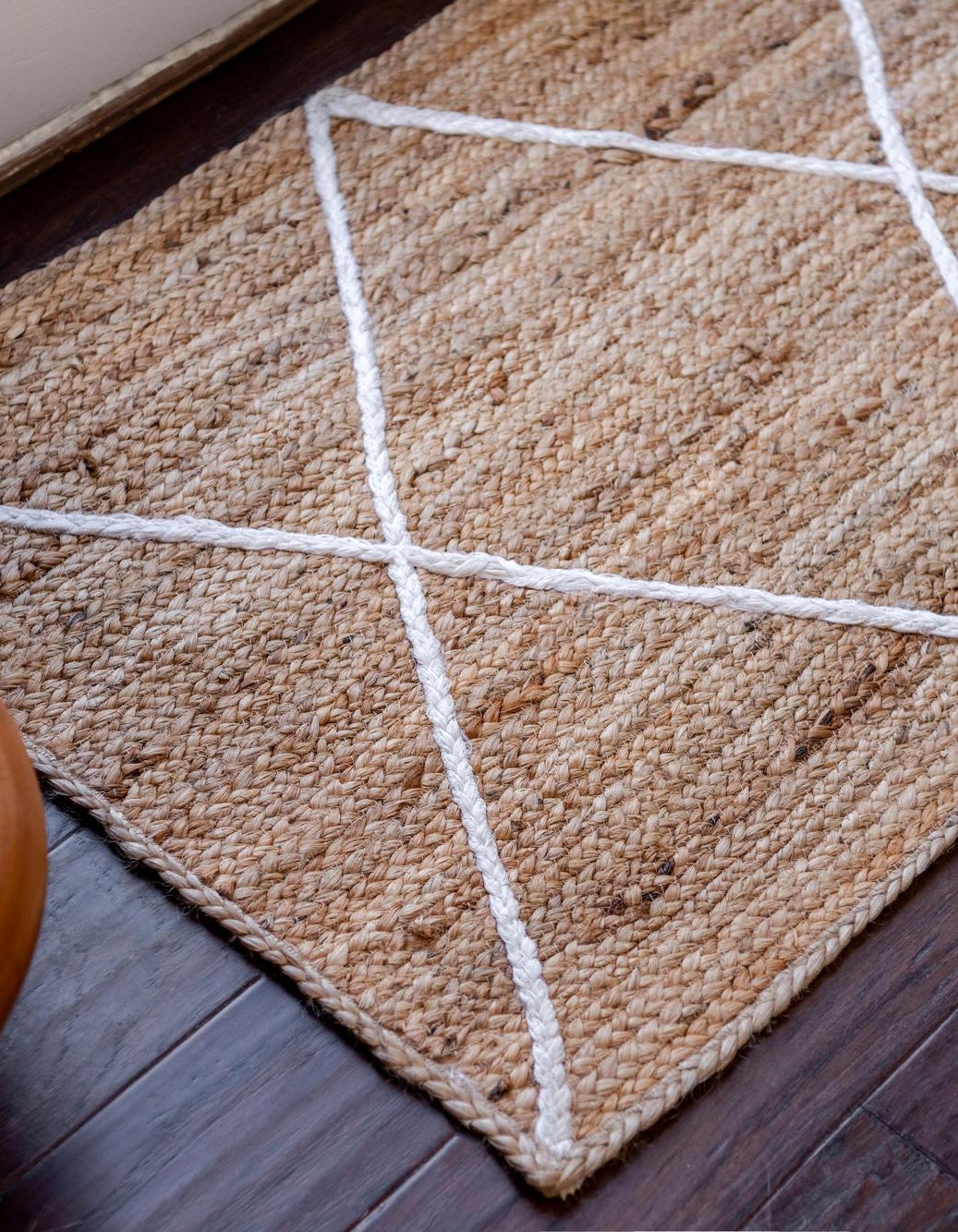 Textured beige rug with white geometric lines on a wooden floor.