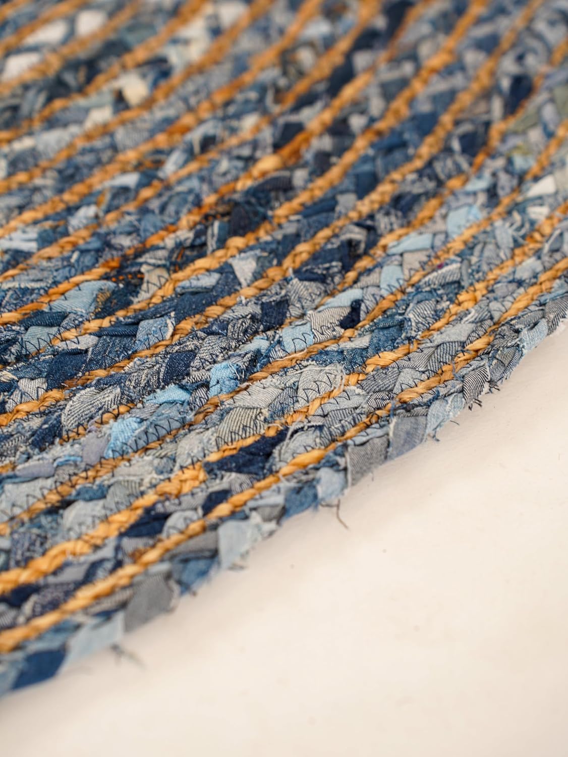 Handwoven blue denim rug with textured stripes and natural jute accents, eco-friendly home decor.