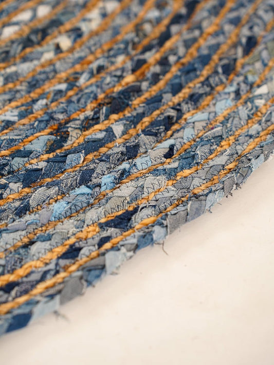 Handwoven blue denim rug with textured stripes and natural jute accents, eco-friendly home decor.