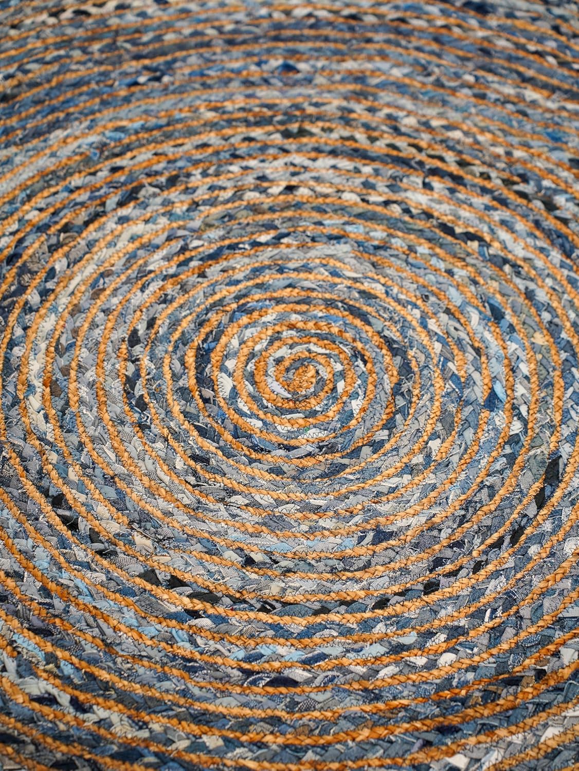 Circular braided rug in blue and orange hues made from durable fabric for home decor.