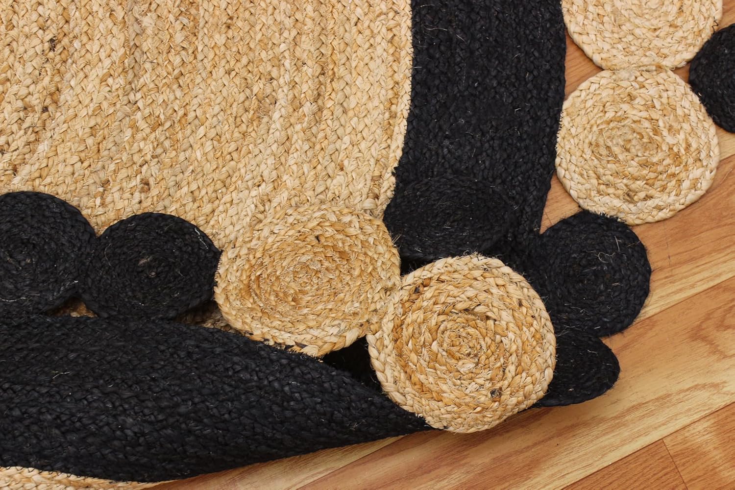 Round braided jute rug with black and natural fiber, featuring decorative spiral patterns.