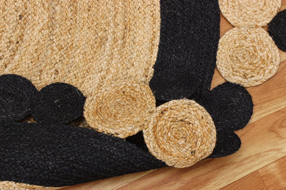 Round braided jute rug with black and natural fiber, featuring decorative spiral patterns.