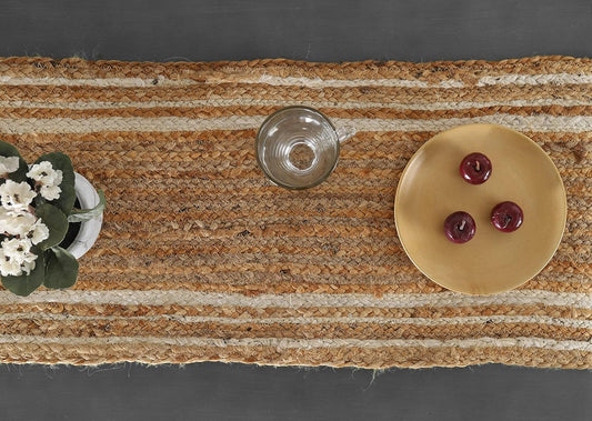 Textured woven mat with a decorative plate, button, and small plant on a dark surface