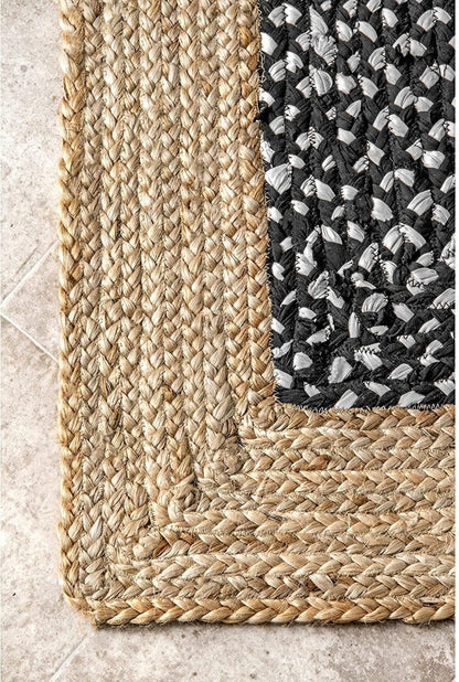 Corner of a woven rug with natural and patterned edges on a tiled floor.