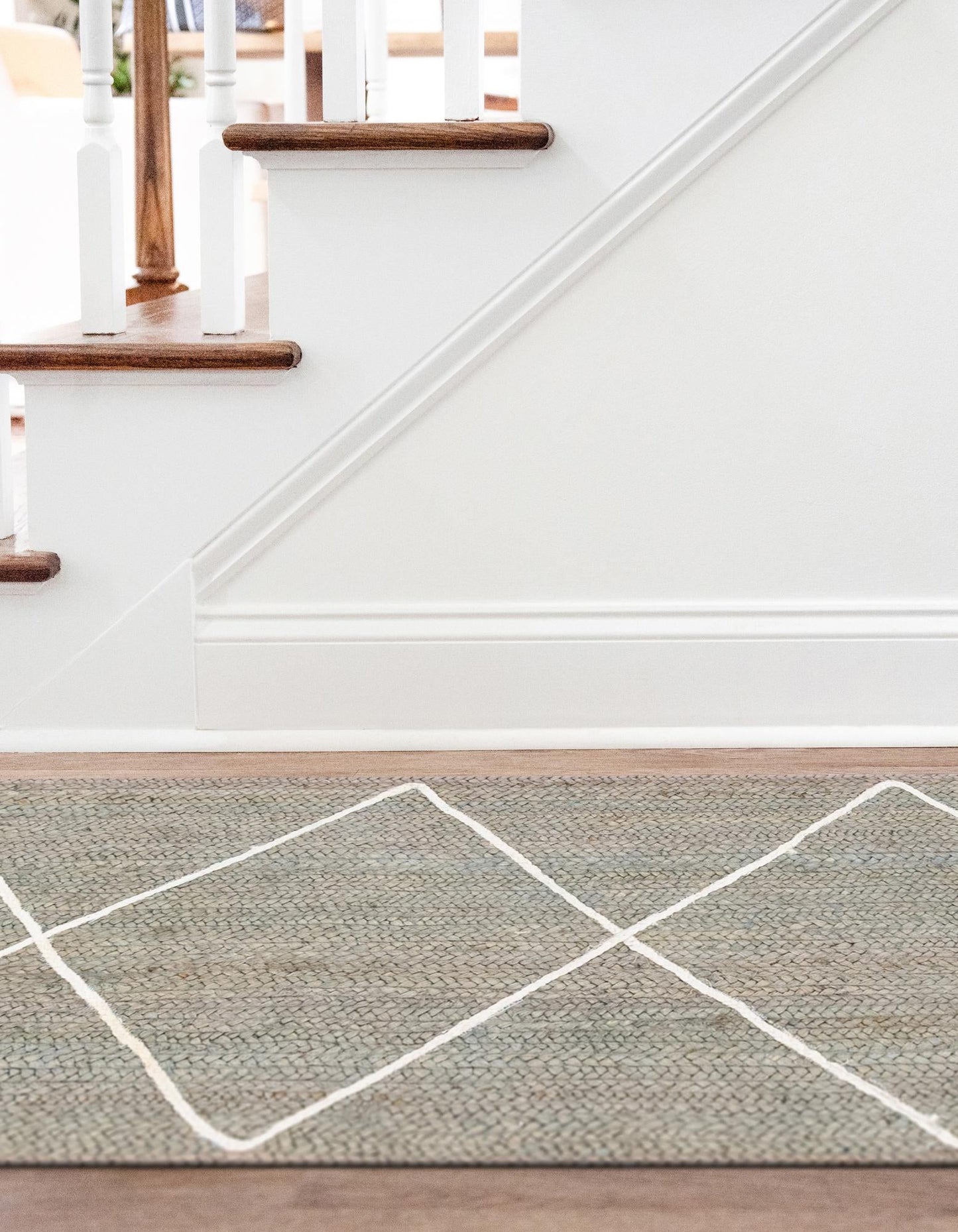 Staircase with a green and white geometric patterned rug on a wooden floor.