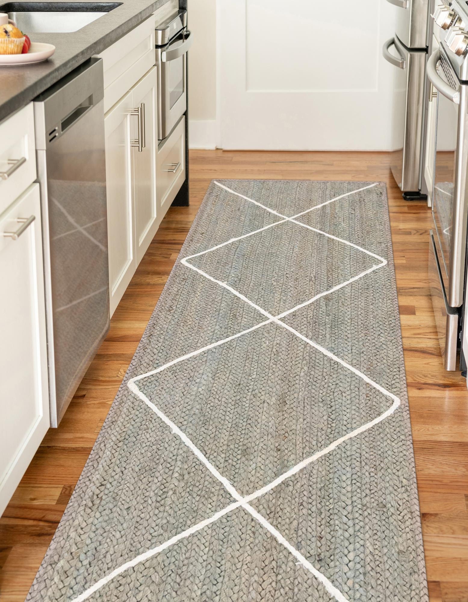 Gray diamond patterned rug on a wooden floor in a kitchen.