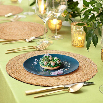 Handmade round jute table placemat with natural braided texture styled on an elegant dining table setting with modern dinnerware