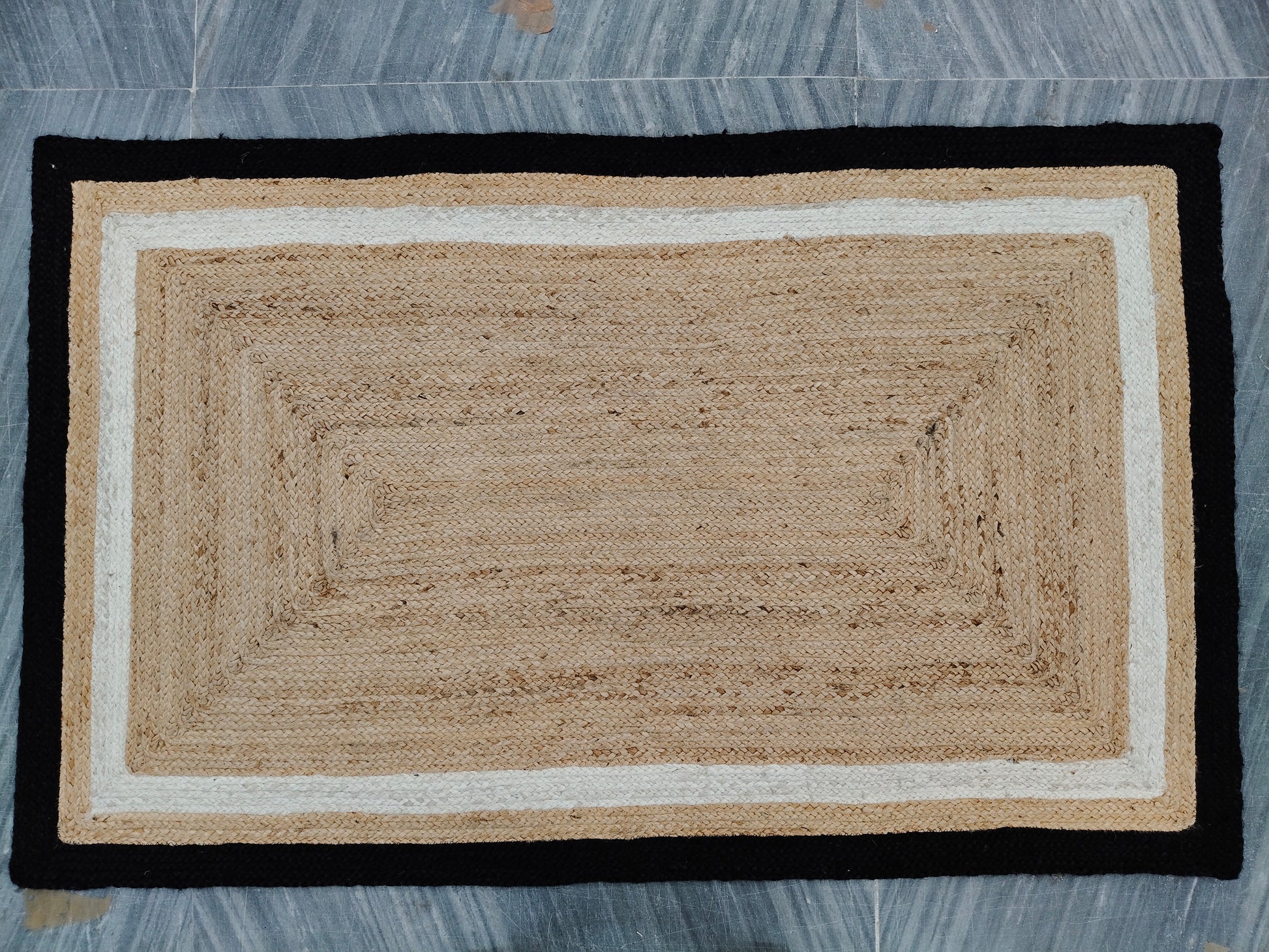 Beige doormat with black border on a tiled floor