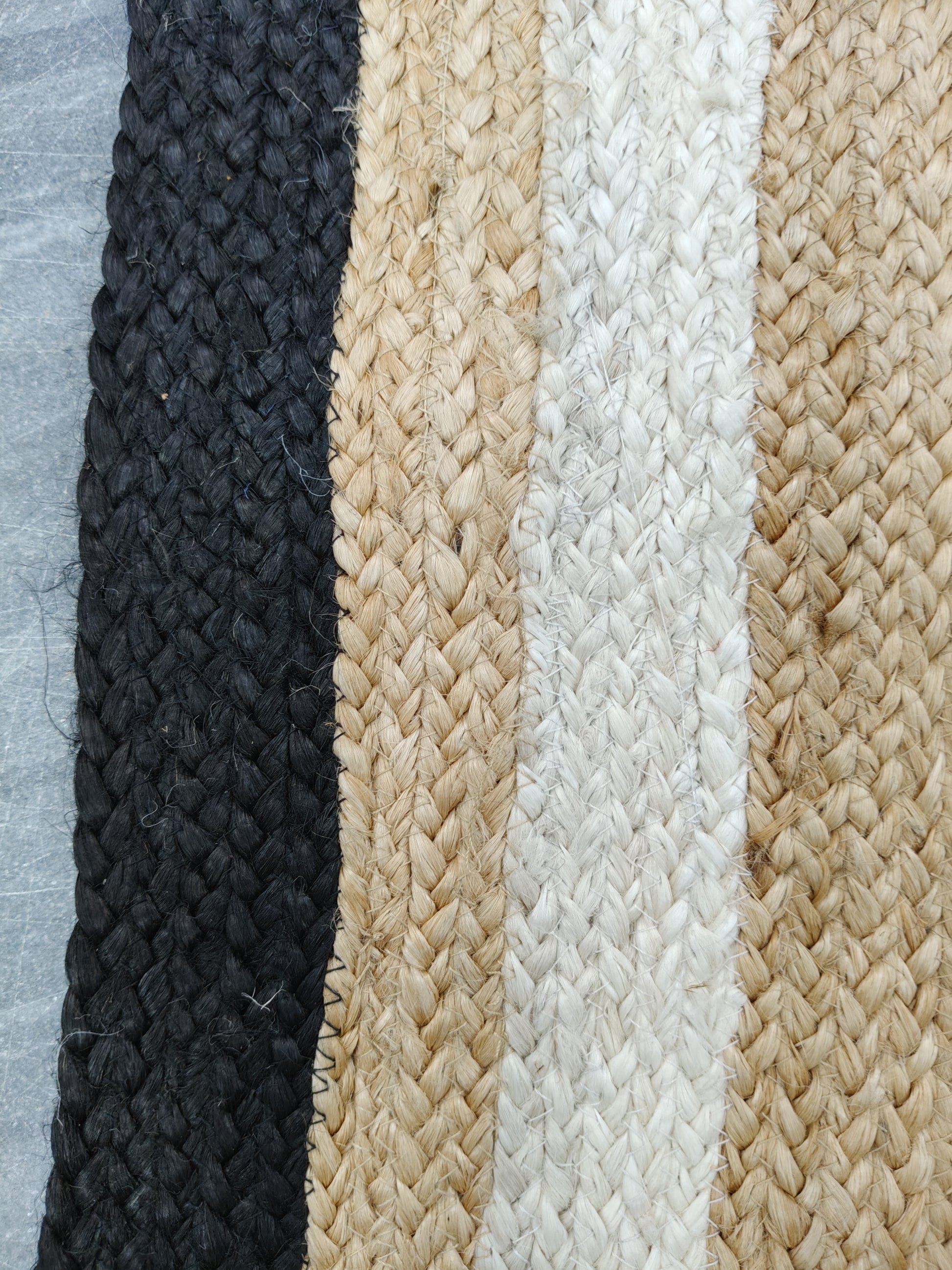 Close-up of braided rope in black, beige, and white on a textured background