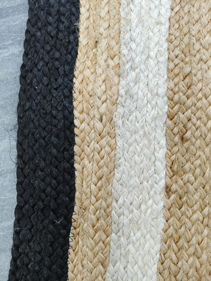 Close-up of braided rope in black, beige, and white on a textured background