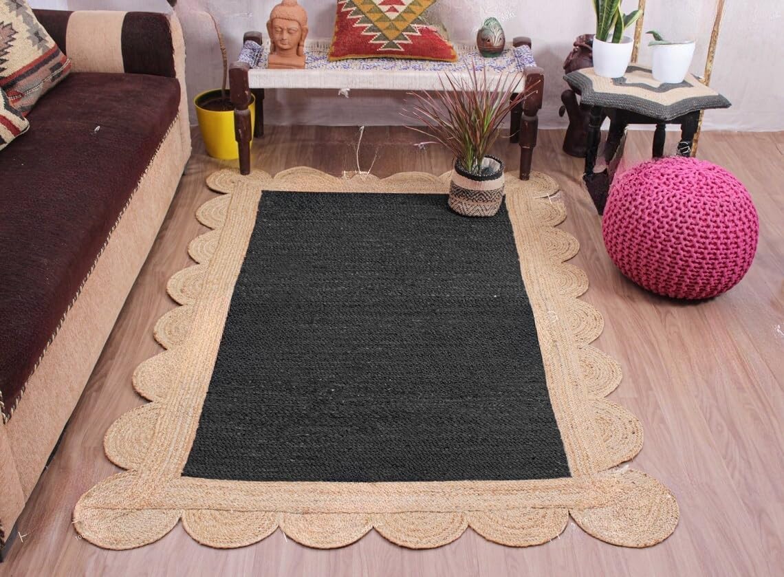A rectangular black woven rug with a scalloped natural jute border, styled on a light wood floor in a living room setting.