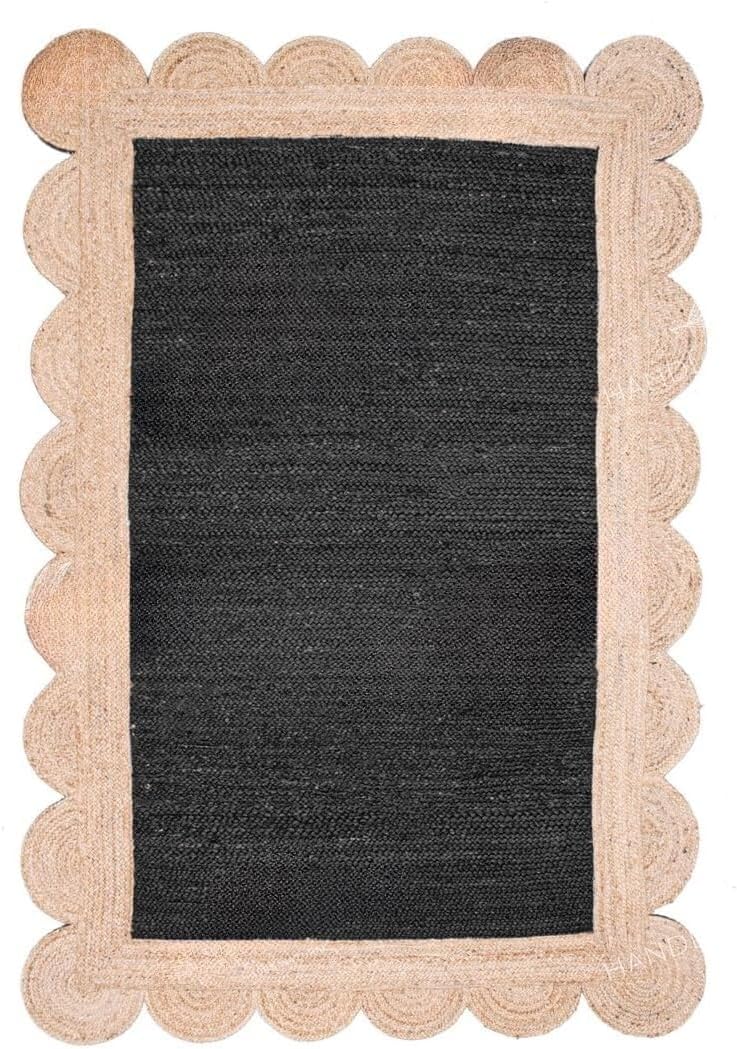 A rectangular woven rug with a dark charcoal gray center and a natural beige scalloped braided border, shown flat against a white background.